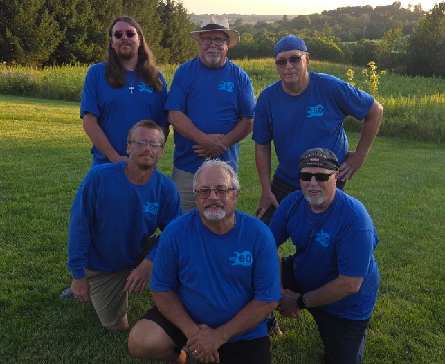 The six members of Blue60 together outside wearing matching blue shirts